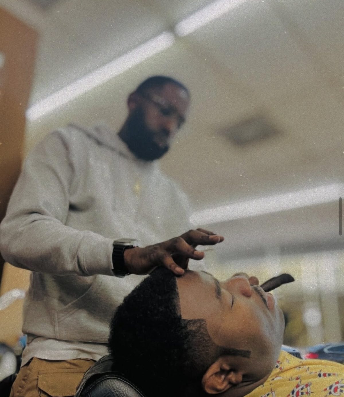 Barber detailing a client's beard inside Headlines Barbershop in Mableton, GA
